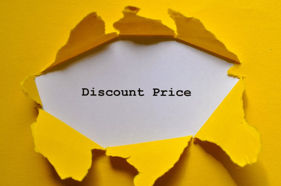 A bright yellow sheet of paper is torn open, revealing a white card inside with the words 'Discount Price' typed in black. The torn edges of the yellow paper have irregular, jagged shapes, and the bac