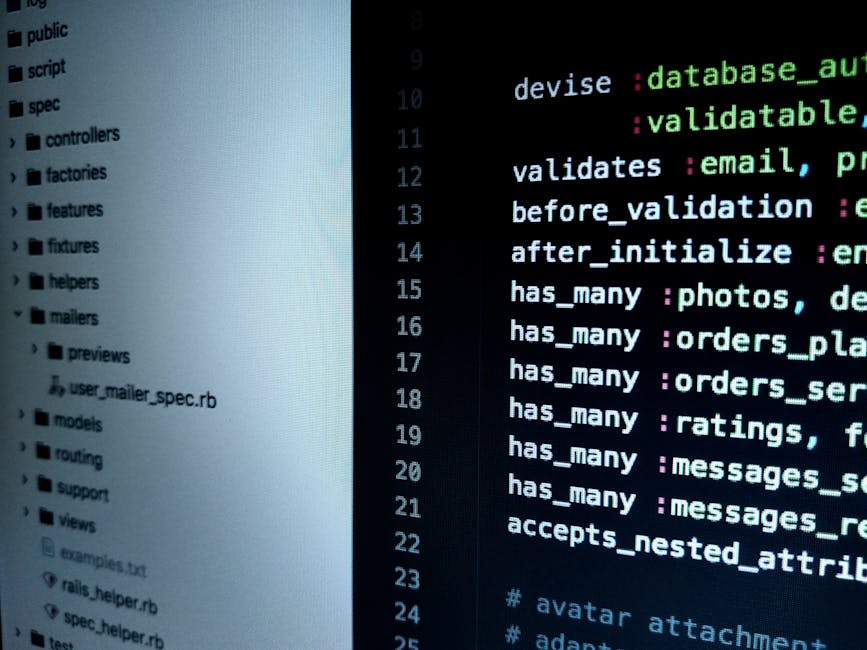 A close-up view of a person's hand wearing a wristwatch, resting on the keyboard of a silver laptop placed on a wooden surface. The laptop screen displays lines of code with syntax highlighting on a d